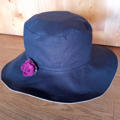 Reversible summer hat with a semi-rigid brim, in dark blue & light grey, featuring a crochet flower from magenta cotton